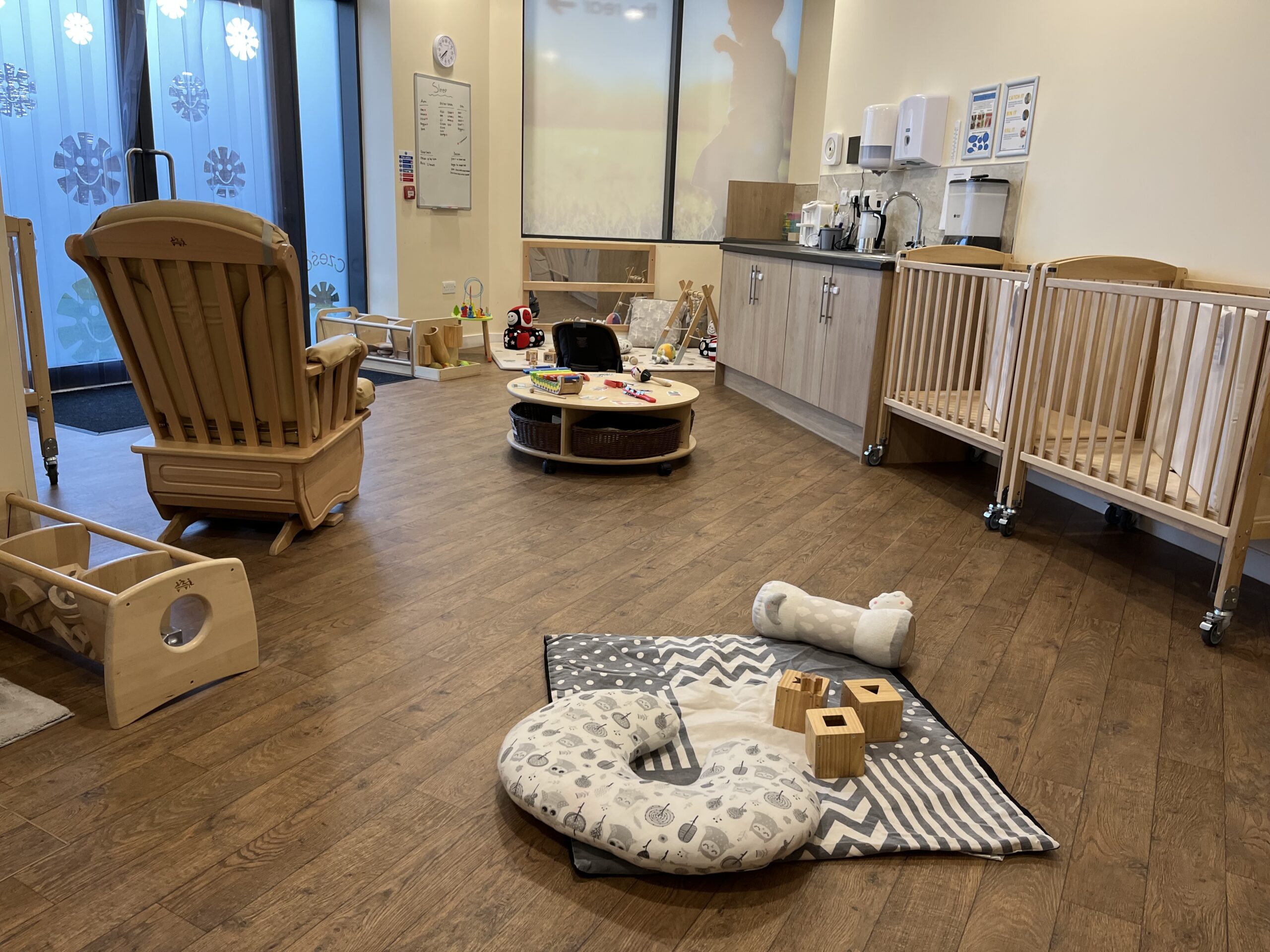 The baby room at charlton heights showing a cot, rocking chair and lots of sensory floor activities