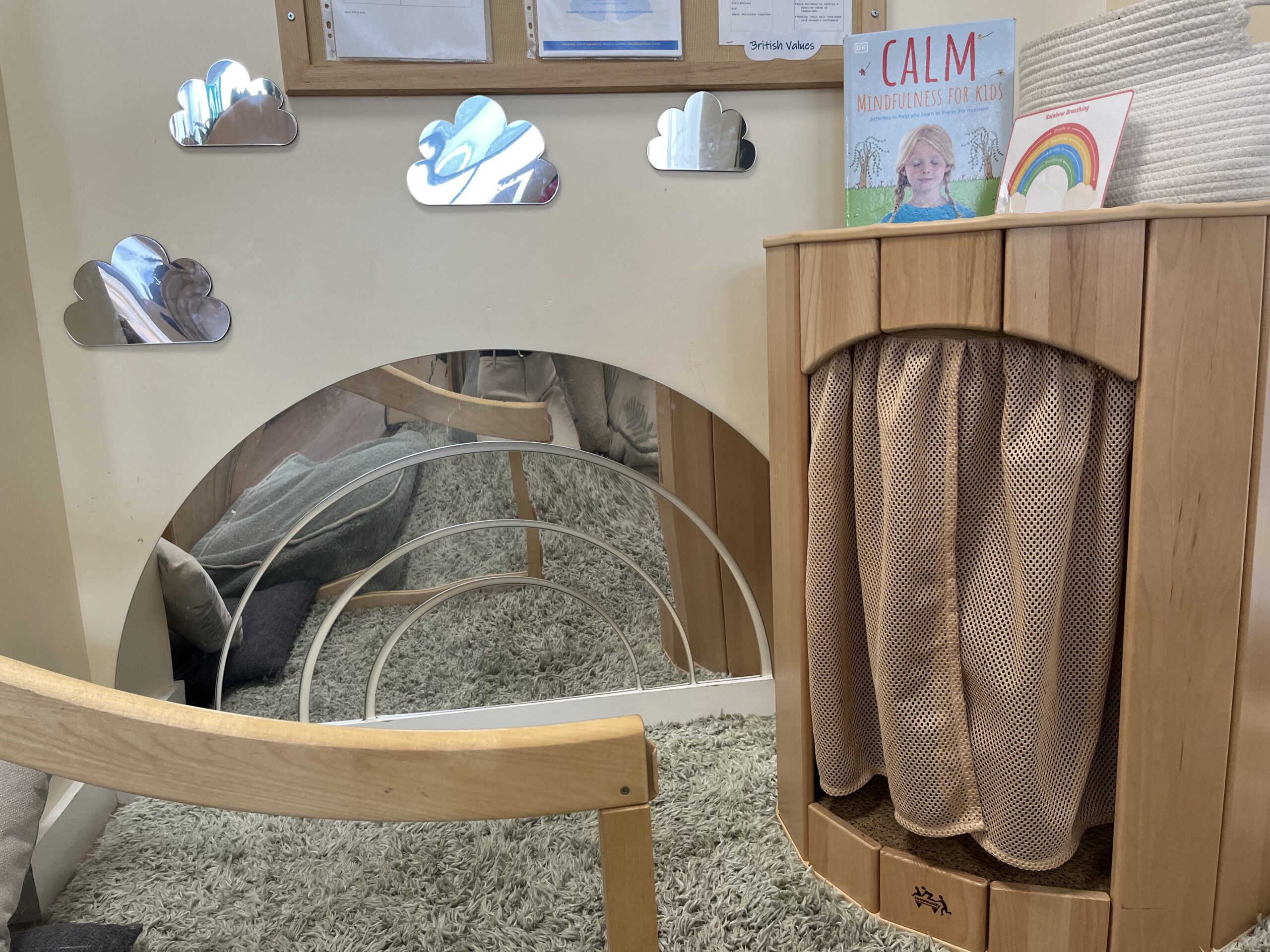a cosy corner with mirrors in the shape of rainbows and clouds as well as a quiet booth with curtain children can go inside if they want to