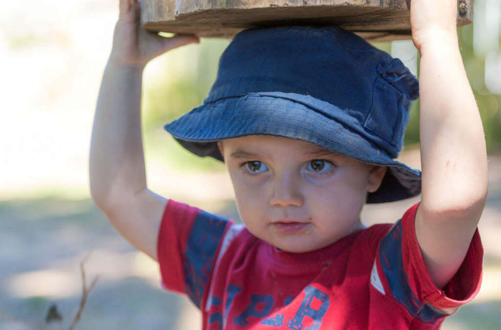 Dziecko w kapeluszu bawiące się na świeżym powietrzu