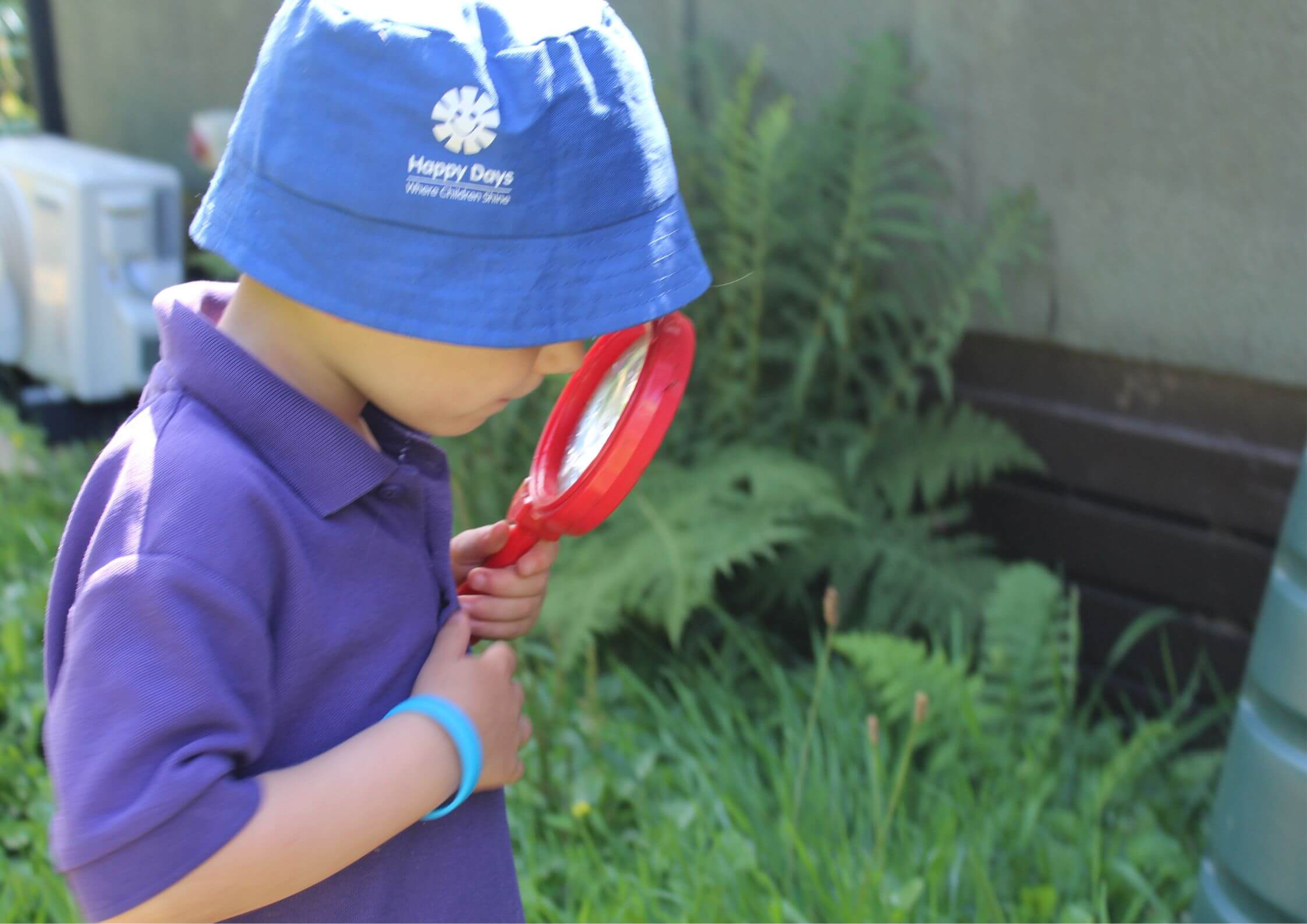 Child exploring outdoors with magnifying glass