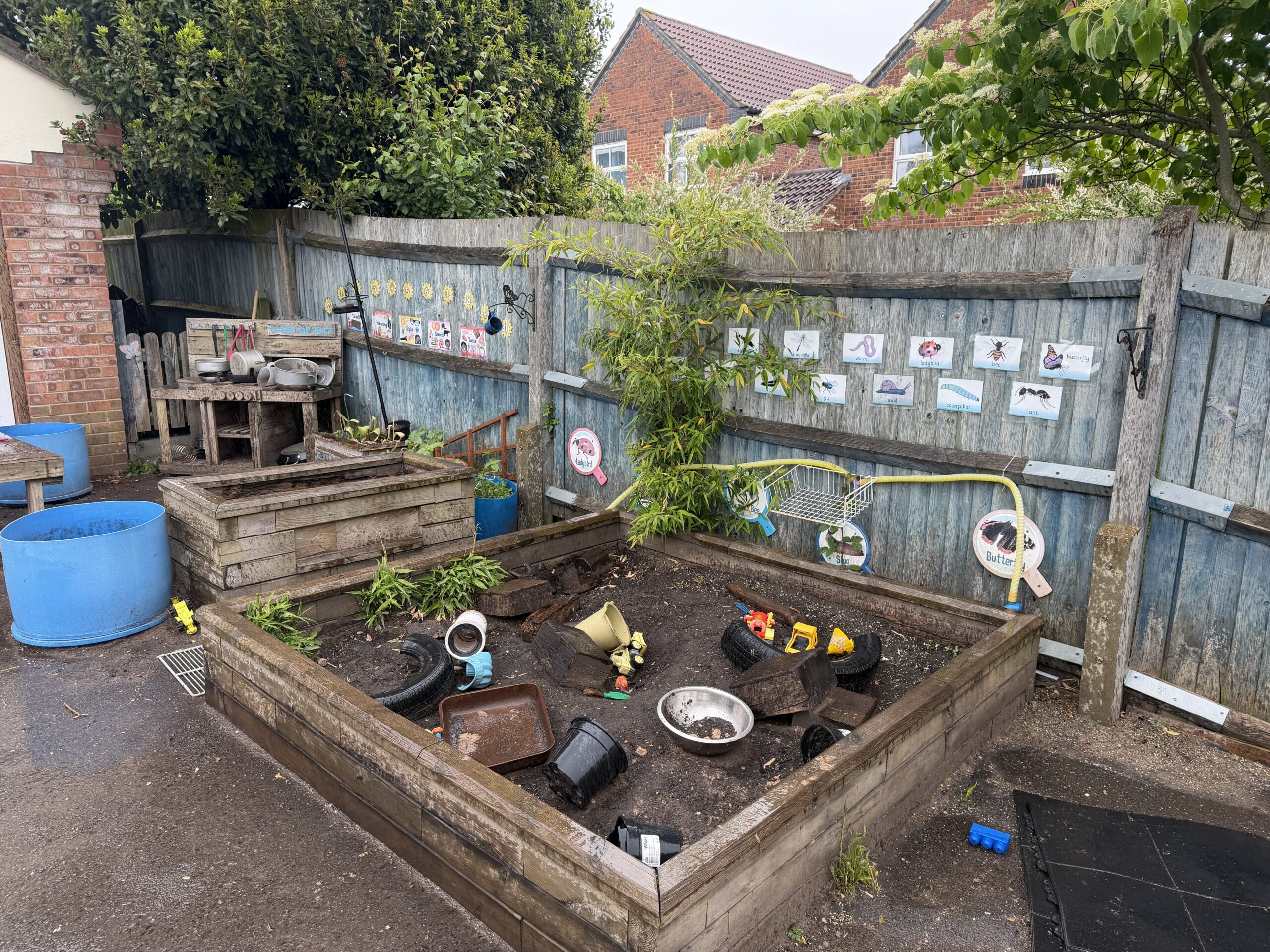 garden area set up with lots of play equipment and resources including a planting area
