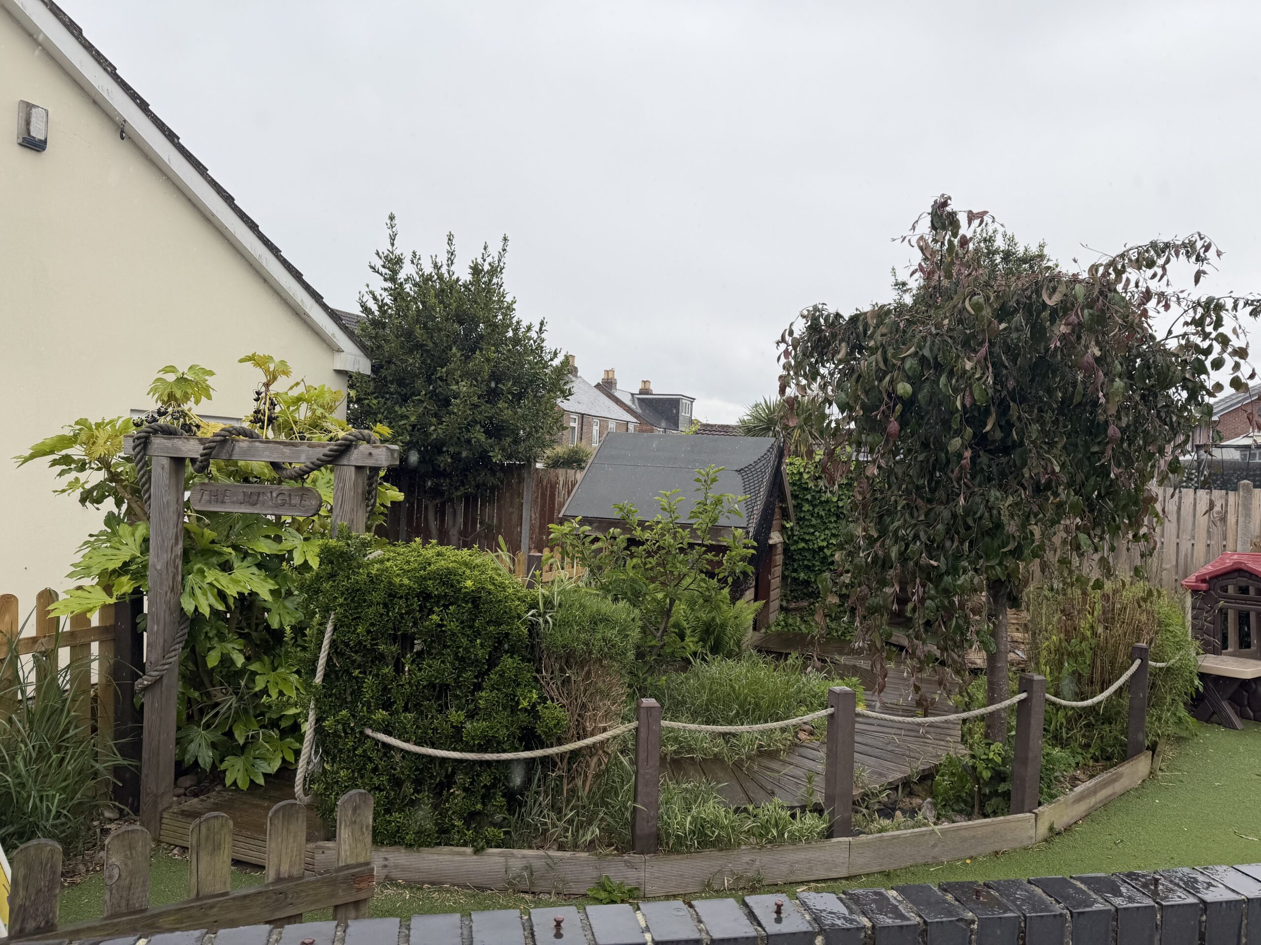 jungle play area in garden with lots of plants and hides for children